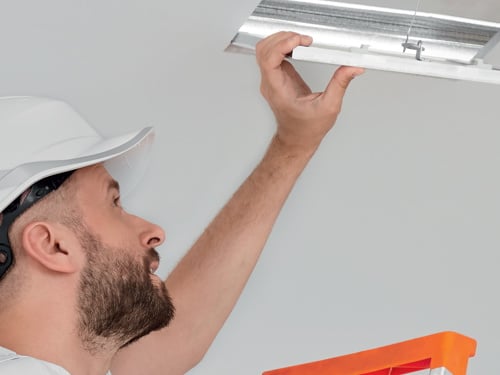Muncitor monteaza o trapa de acces pe tavan